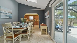 A dining area with a table set for six, a kitchen in the background, and a patio visible through glass doors. - HEATED Saltwater POOL, Harry Potter, BBQ, Lake, Fishing, Gazebo, Games & Firepit (St. Augustine)