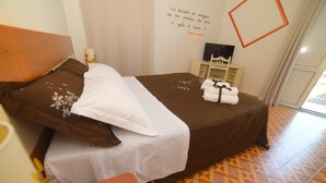 A neatly made bed with a brown headboard, a white pillow, and a brown blanket. There is a remote control on a wooden side table next to the bed. - Lamezia Terme family apartment "girasoli" (Lamezia Terme)