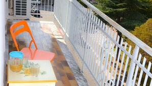 A balcony with a table and chairs, a white railing, and a view of buildings and trees. - Lamezia Terme family apartment "girasoli" (Lamezia Terme)