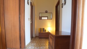 A hallway with patterned floor tiles, wooden doors, a dresser, and a mirror on the wall. - Lamezia Terme family apartment "girasoli" (Lamezia Terme)