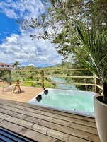 A wooden deck with a hot tub, a chair, and a table.