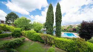 Ein angelegter Garten mit Schwimmbad, hoch aufragenden Zypressen und einer Backsteinmauer.