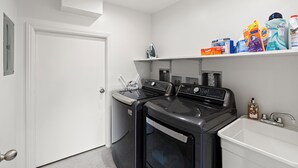 A laundry room with a washing machine, dryer, and a shelf with laundry detergent. - Amazing House On The Beach!! (Watsonville)