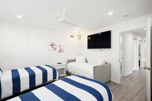 Ein modernes Schlafzimmer mit zwei Betten, einem Fernseher und einem Deckenventilator.