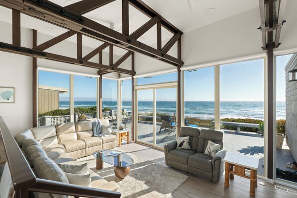 A spacious living area with a large window overlooking the ocean, furnished with a sofa and a coffee table. - Amazing House On The Beach!! (Watsonville)