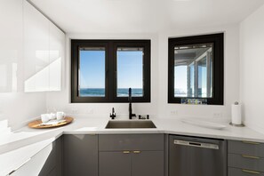 A modern kitchen with a stainless steel sink, two windows with ocean views, and a Bosch dishwasher. - Amazing House On The Beach!! (Watsonville)
