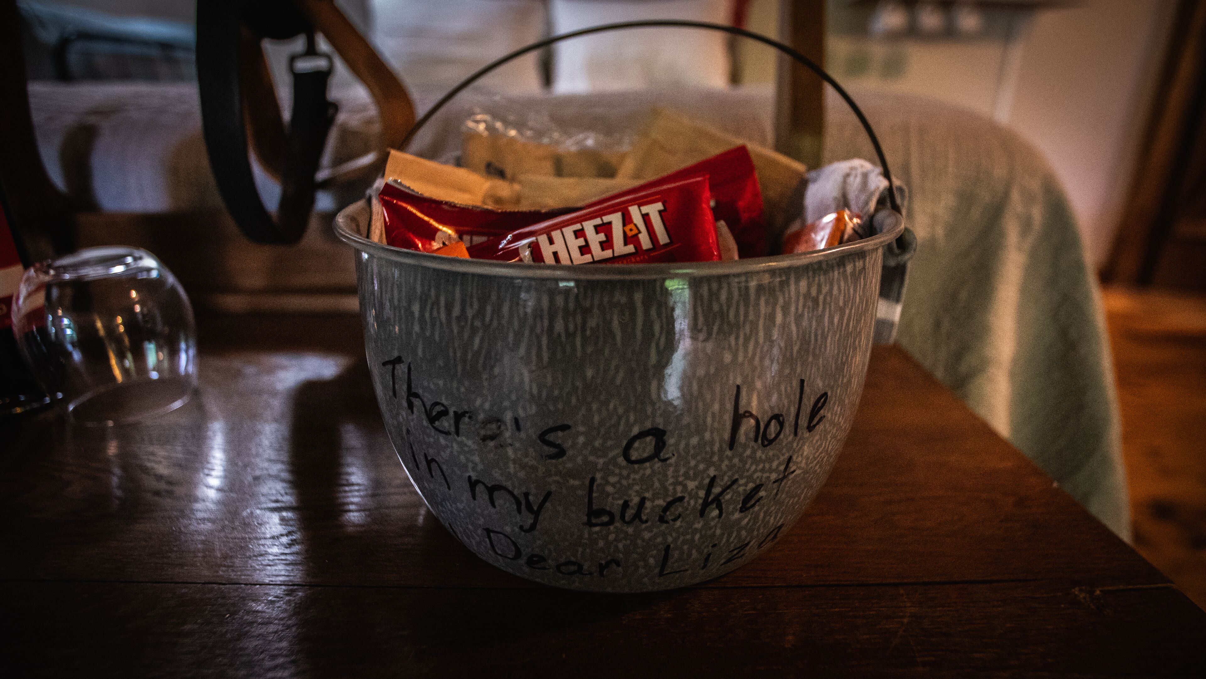 A metal bucket with a handwritten message on a wooden table.