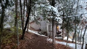 A snow-covered path leading to a rustic wooden building surrounded by trees. - Cowboy Cabin, come sit under the trees (Marthasville)