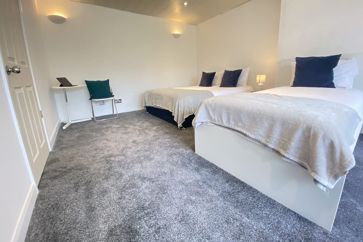 A hotel room with two beds, a desk, and a chair.