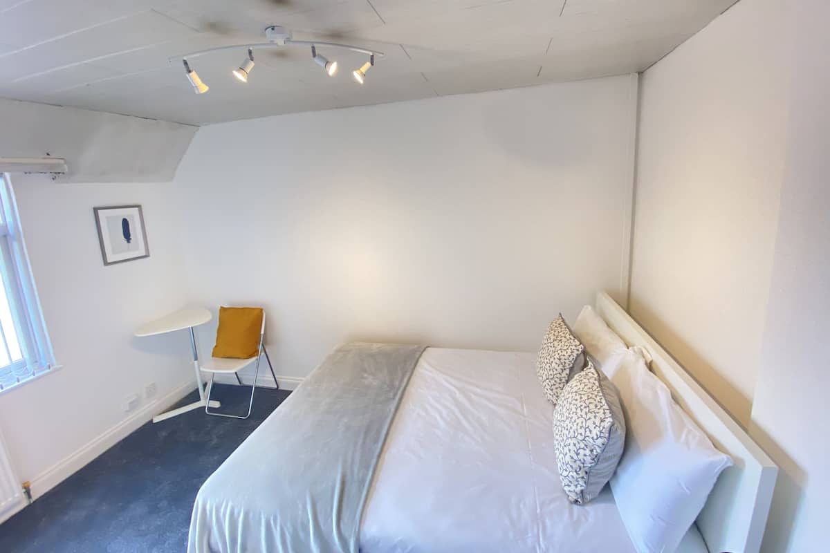 A bedroom with a bed, a desk, and a chair.