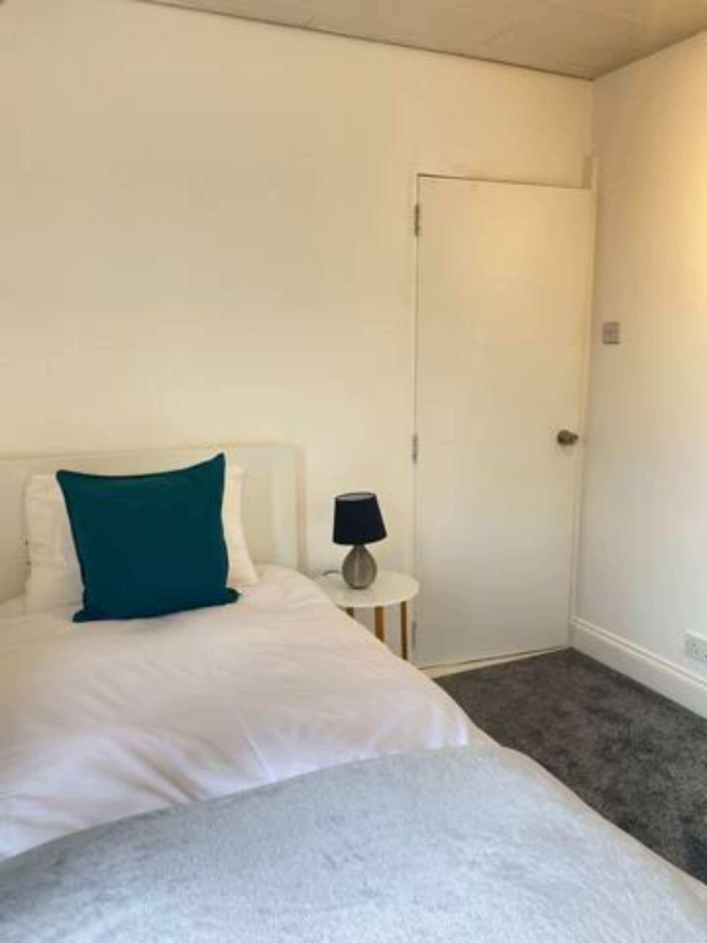 Ein Hotelzimmer mit Bett, Nachttisch und Tür.