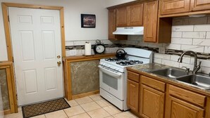 Une cuisine compacte avec des meubles en bois, une cuisinière blanche, un évier et un dosseret carrelé.