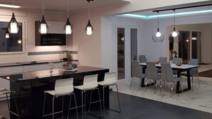 Une cuisine moderne dotée d’un îlot central, de luminaires suspendus et d’un luminaire encastré au plafond.