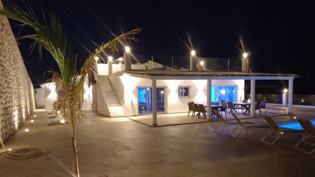 Une villa moderne dotée d’une piscine, d’un espace extérieur aménagé et d’un escalier menant à l’intérieur.