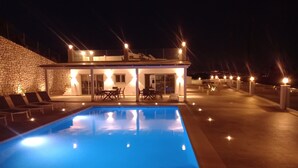 Un espace aménagé au bord de la piscine, comprenant une piscine, des chaises longues et un bâtiment à la façade en pierre.