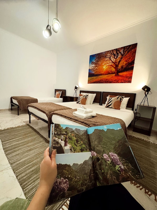 Un dormitorio moderno con una cama grande, un cuadro de un árbol y un libro sobre la cama.