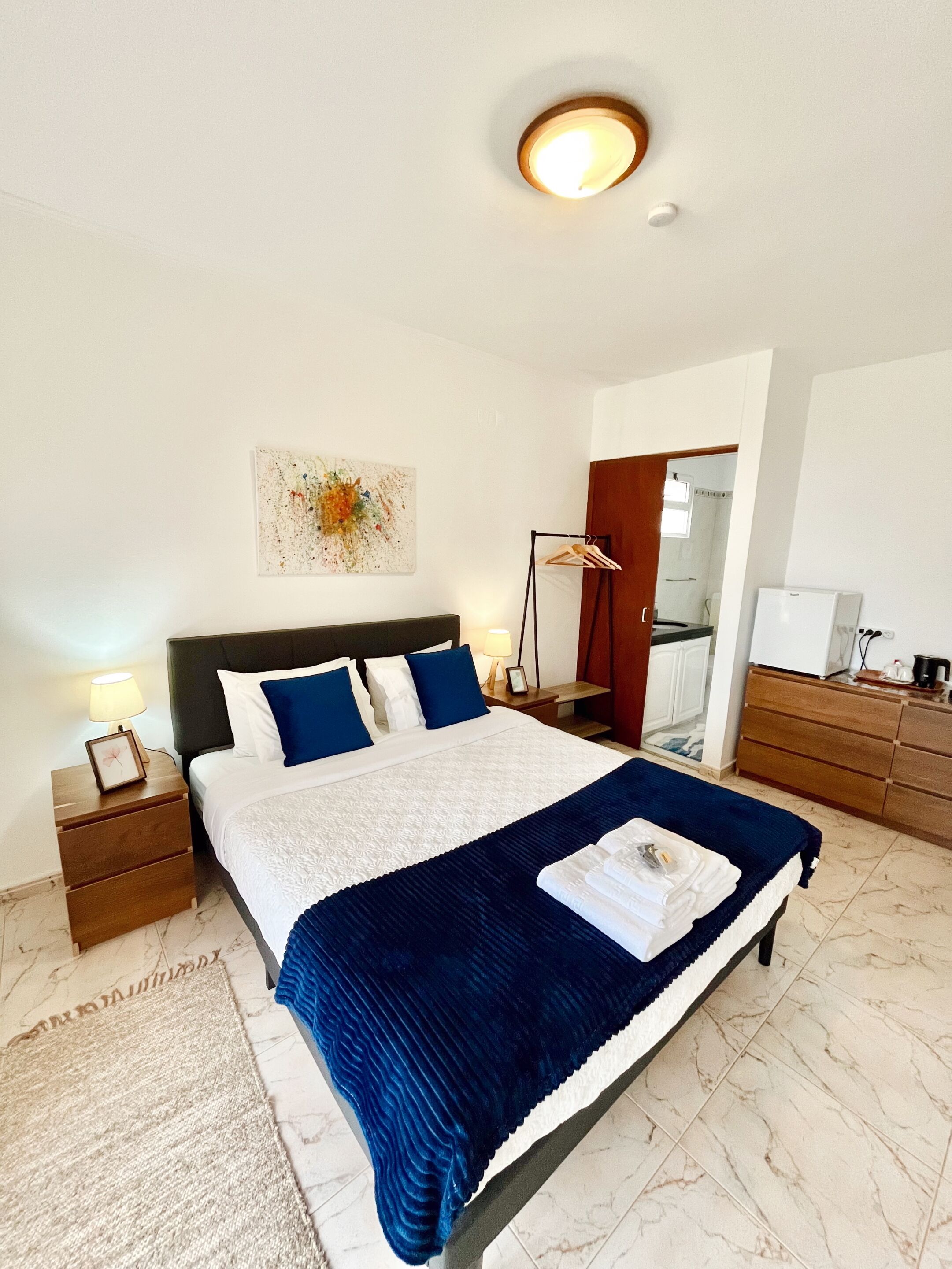 Une chambre à coucher bien rangée, avec un lit, des tables de chevet, une commode, une coiffeuse et un miroir.