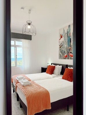 Une chambre d’hôtel moderne avec deux lits, une grande fenêtre, un luminaire au plafond et un tableau mural.