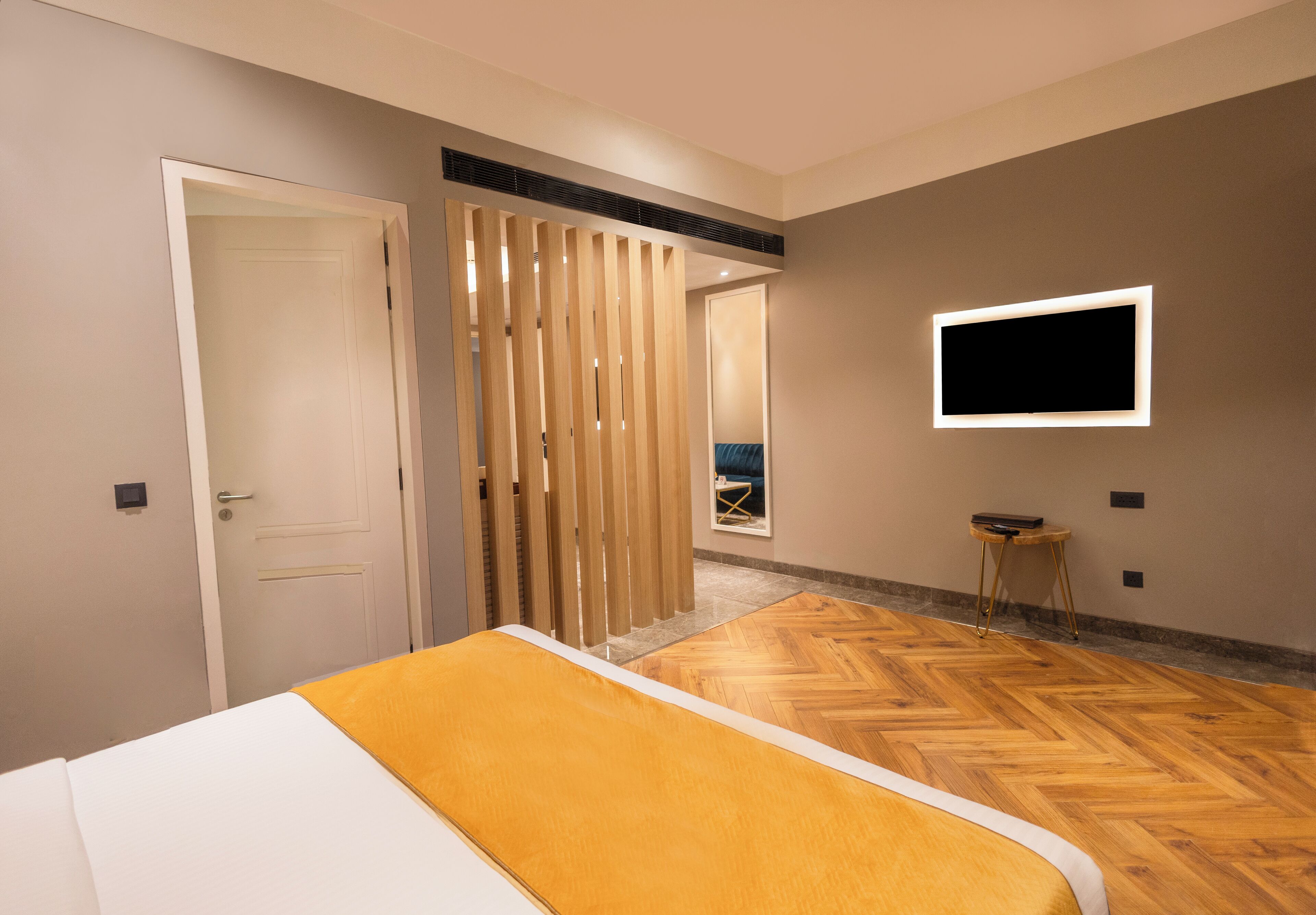 A hotel room with a bed, a TV mounted on the wall, and a sliding door leading to another room.