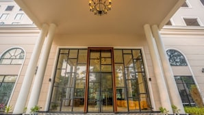 A hotel entrance with a glass door, white columns, and a chandelier. - Polo Hotel, Agartala (Agartala)