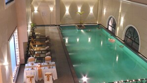 An indoor swimming pool with a dining area adjacent to it, featuring tables set for a meal and a small plant in the pool. - Polo Hotel, Agartala (Agartala)