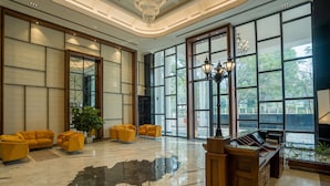 A spacious lobby with large windows, yellow sofas, a reception desk, and a chandelier. - Polo Hotel, Agartala (Agartala)