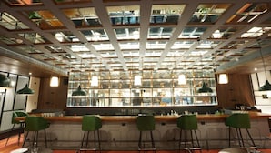 A bar area with a modern design, featuring a glass partition and multiple hanging lights. - Polo Hotel, Agartala (Agartala)