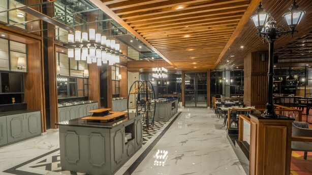 A modern restaurant interior with a marble floor, wooden ceiling, and glass walls. - Polo Hotel, Agartala (Agartala)