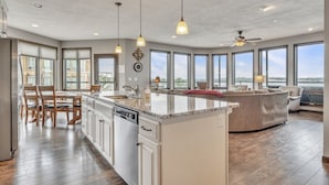 Une cuisine spacieuse dotée d’un grand îlot central, de meubles en bois et offrant une vue sur l’extérieur.