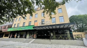A multi-story building with a covered entrance and a green awning. - James Joyce Coffetel Shanghai Zhuanqiao Wanda Plaza (ex Shanghai James Joyce Coffetel Zhuan Bridge W (Shanghai)