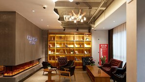 A modern lounge area with a fireplace, seating, and a bookshelf filled with books and decorative items. - James Joyce Coffetel Shanghai Zhuanqiao Wanda Plaza (ex Shanghai James Joyce Coffetel Zhuan Bridge W (Shanghai)