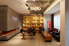 A modern lounge area with a fireplace, seating, and a bookshelf filled with books and decorative items. - James Joyce Coffetel Shanghai Zhuanqiao Wanda Plaza (ex Shanghai James Joyce Coffetel Zhuan Bridge W (Shanghai)