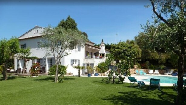 Una casa grande y blanca con piscina y césped verde.