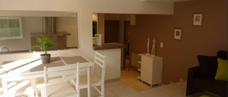 A modern living space with a dining area, kitchen, and seating area.