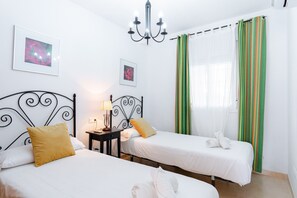 Habitación de hotel con dos camas, una mesita de noche, una lámpara y un candelabro.
