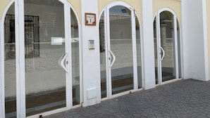 A building entrance with three arched glass doors, a sign reading "PORTAL 1", and a keypad lock. - Chimenea Pinar 2 Apartment by Casasol (Nerja)