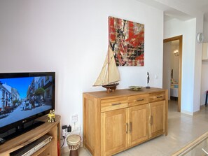 Un salon avec un téléviseur, un meuble en bois et une maquette de voilier.