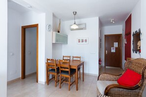 Un coin repas avec une table et des chaises en bois, un téléviseur fixé au mur et un appareil de climatisation fixé au mur.