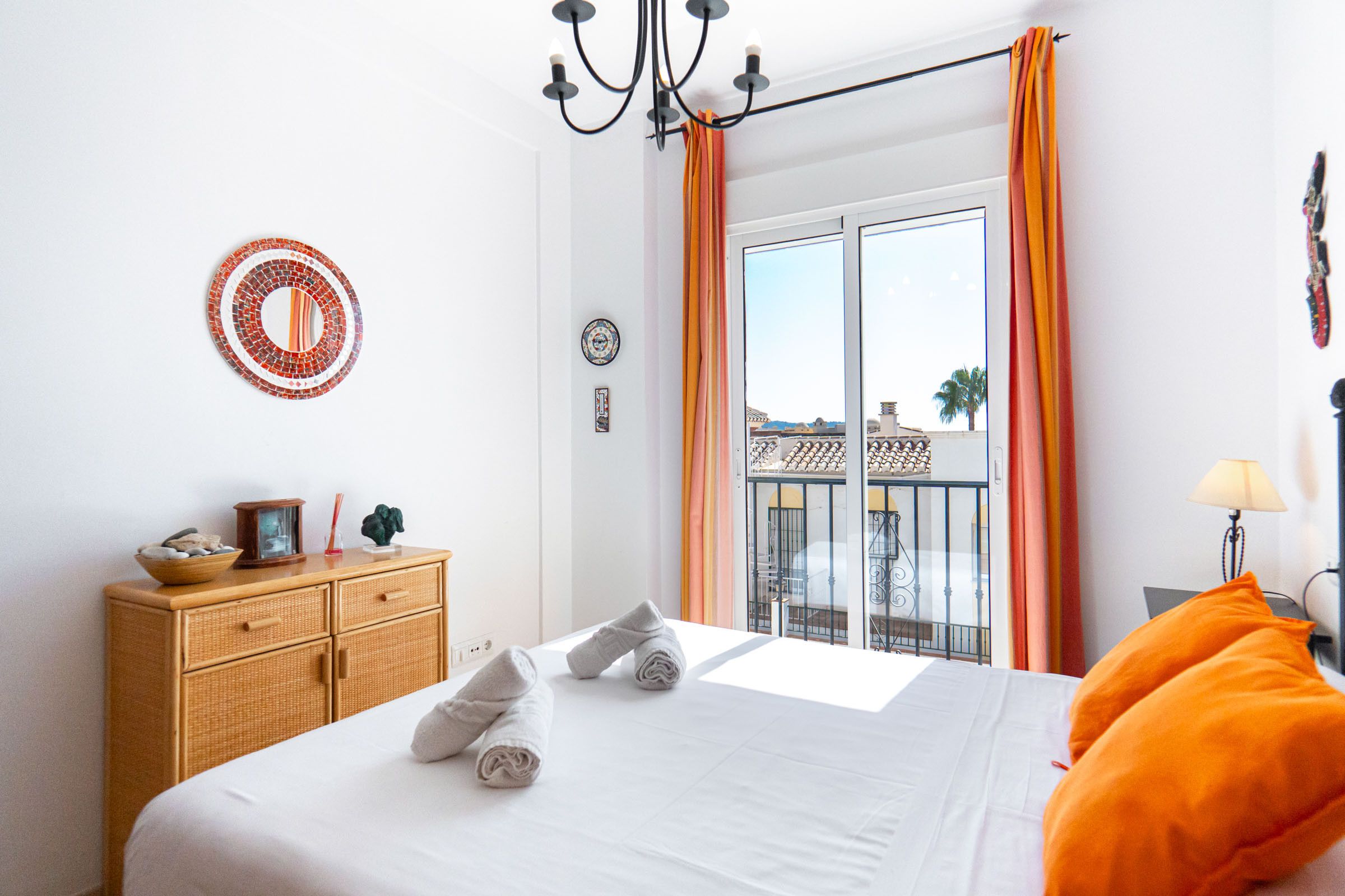Een hotelkamer met een bed, een dressoir, een raam met gordijnen en een balkon met een balustrade.