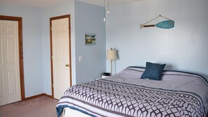 Een slaapkamer met een bed, een plafondventilator, een wandlamp en een deur.