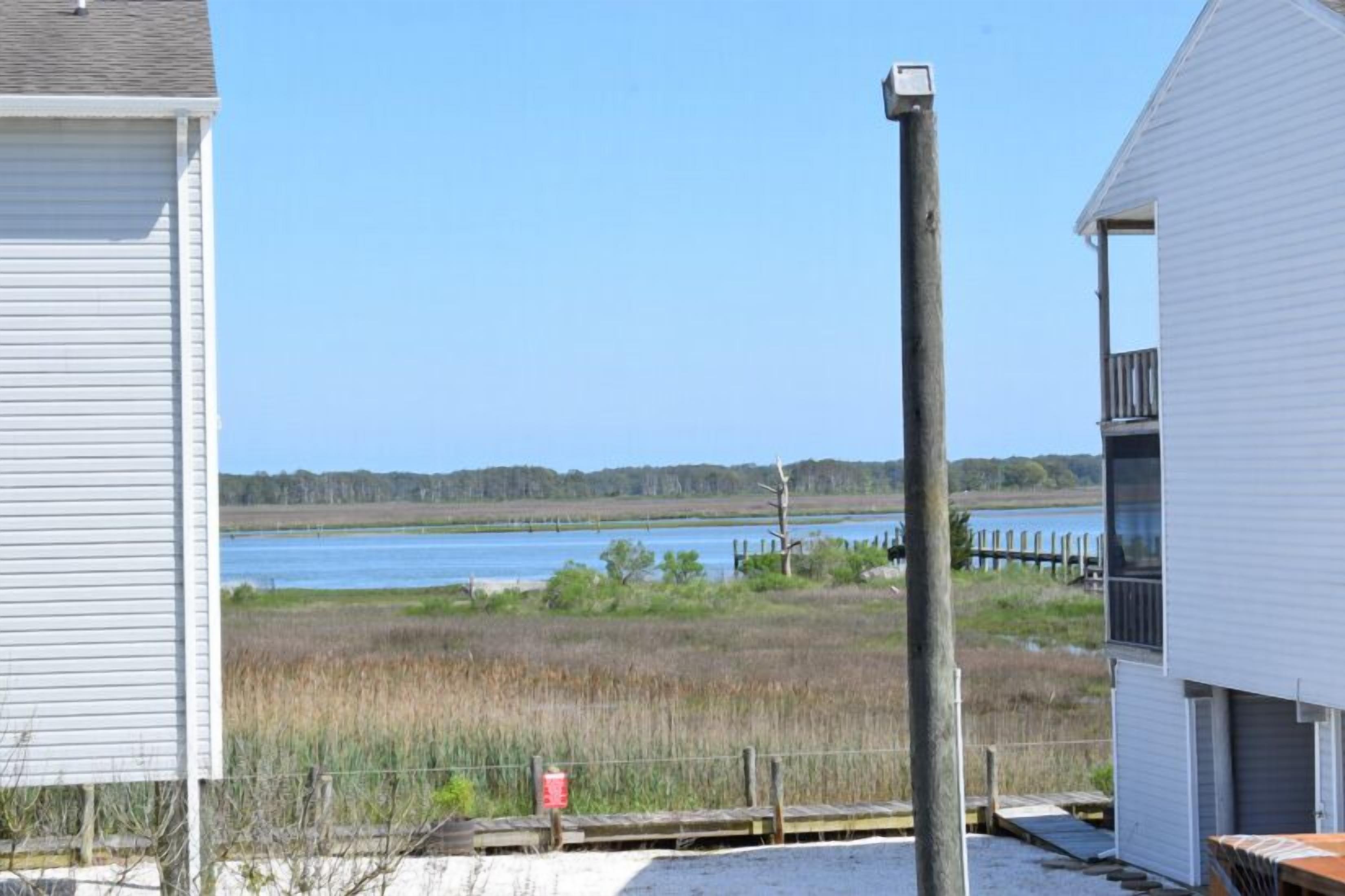 A coastal house with a view of a lake and a wooden dock.