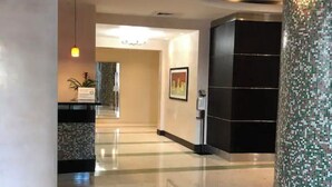 Hall dell'hotel con pavimento lucido, una reception, un quadro incorniciato al muro e un pilastro decorativo.
