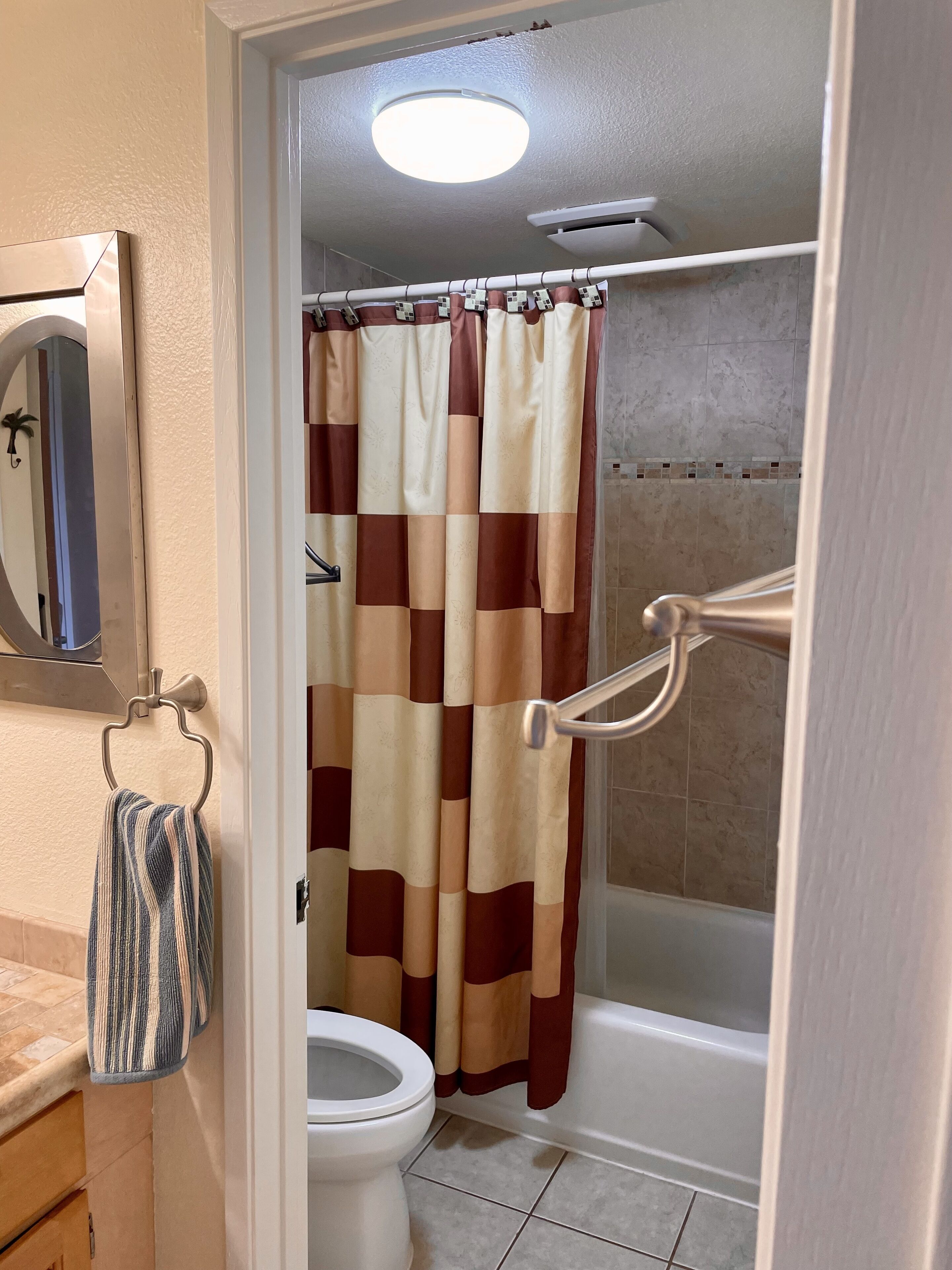 A bathroom with a toilet, shower, and a towel rack with a towel.