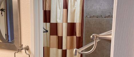 Een badkamer met toilet, douche en een handdoekrek met een handdoek.