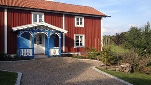 Punainen talo, jossa on sininen kuisti ja valkoiset koristeet.