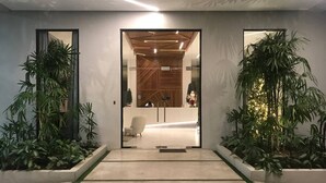 Un área de recepción moderna con puerta de cristal, mostrador de recepción y zona de estar.