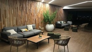 Una sala moderna con un sofá seccional, dos sillones, una mesa de centro y una planta grande en maceta.