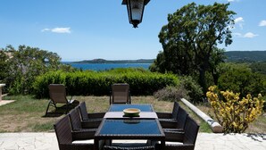 Un patio al aire libre con mobiliario de mimbre, una mesa con un cuenco y un farol colgante.