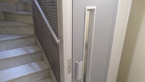 Un escalier muni d’une rambarde de sécurité en métal, une porte avec une poignée et une petite fenêtre.