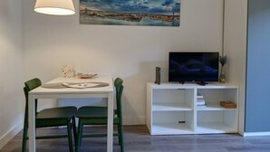 Un salon moderne avec une table à manger, des chaises, un téléviseur et un tableau accroché au mur.